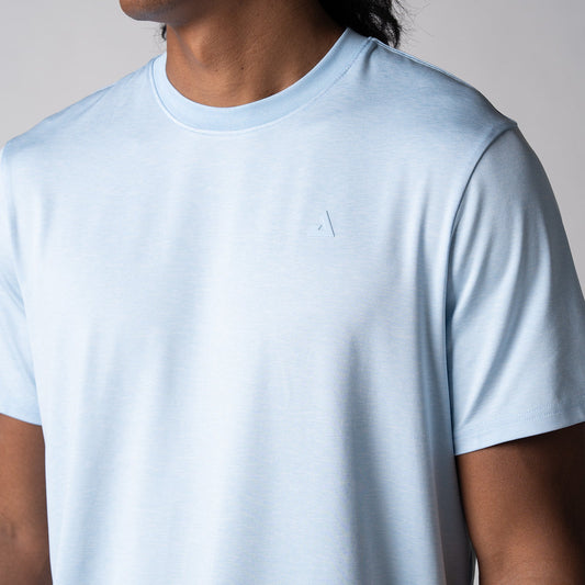 Gray background, close up of the JOOLA trinity logo over the left chest of a male model wearing a JOOLA Men's Club Short Sleeve, Blue Breeze.