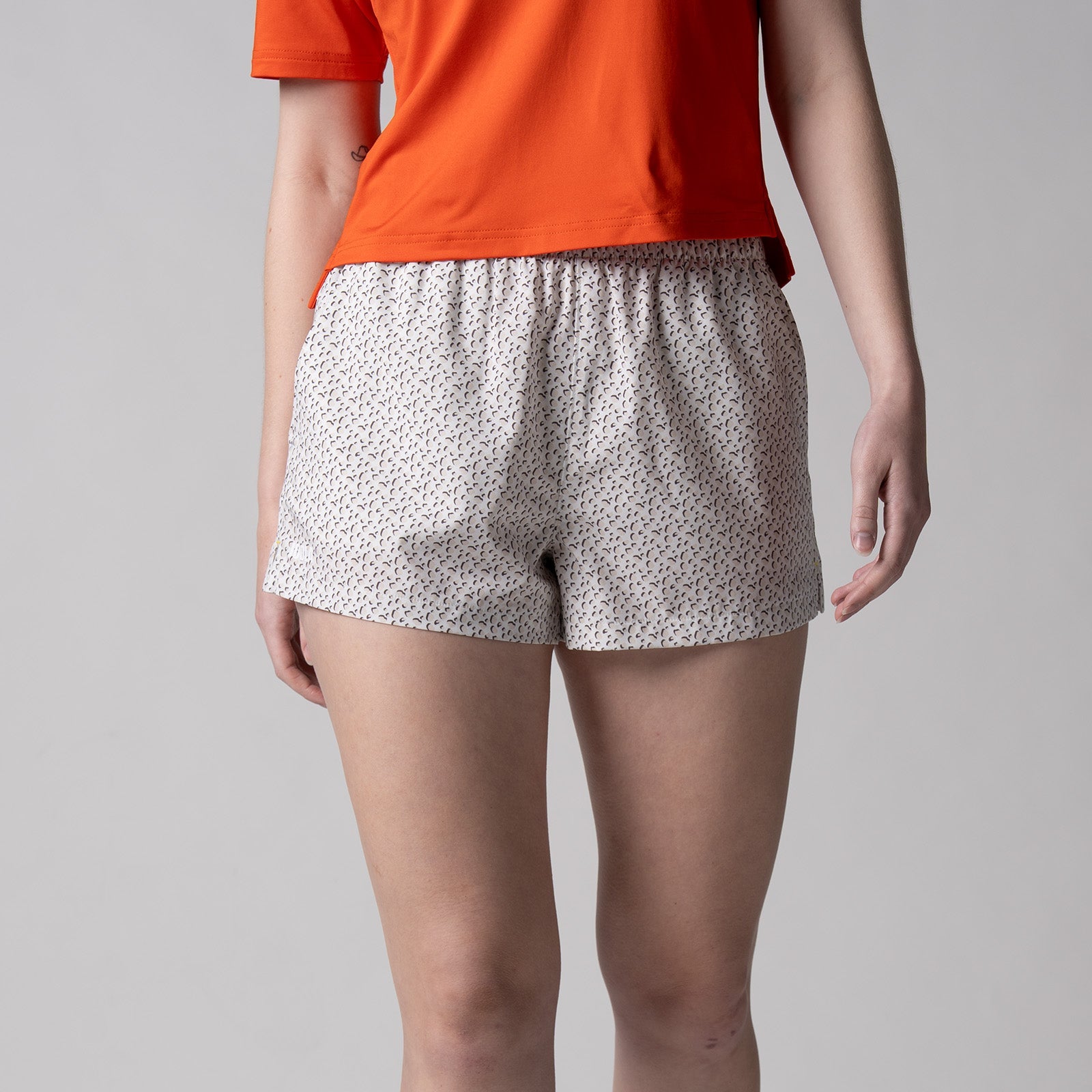 Gray background, image of a female model wearing a JOOLA women's court woven printed shorts.