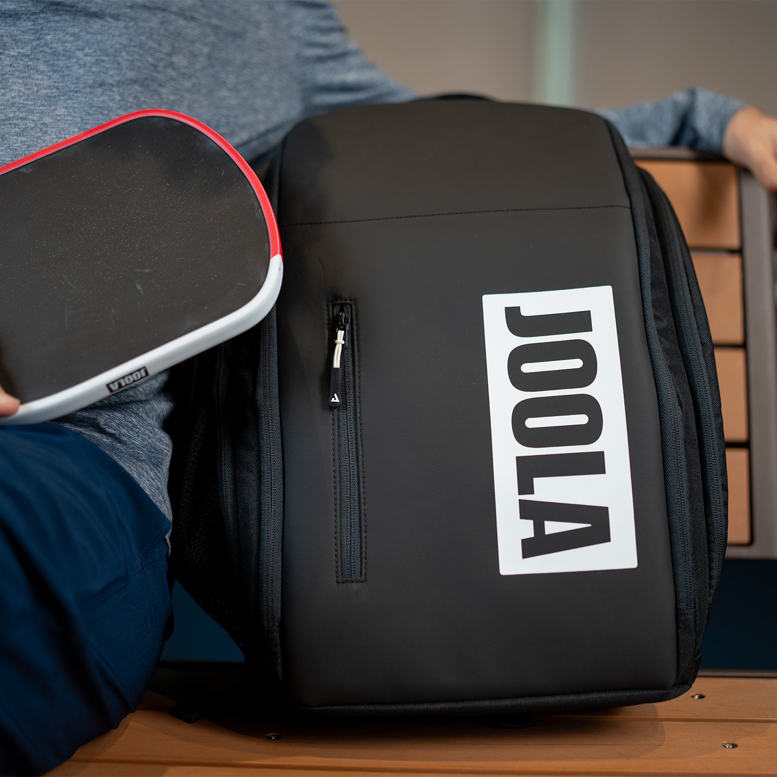 Close up image of the JOOLA Vision II backpack on a bench with the Agassi Pro pickleball paddle featured in frame.