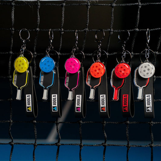 The full set of Agassi and Pro IV colorful table tennis paddle keychains on a black background.